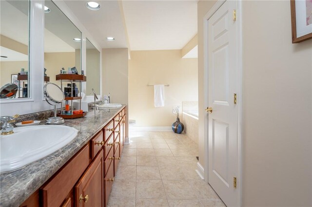 bathroom featuring tile patterned flooring, a garden tub, double vanity, recessed lighting, and a sink