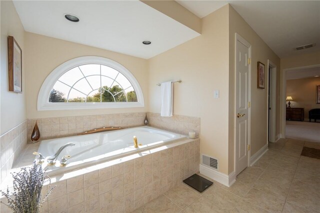 full bath featuring tile patterned floors, a garden tub, and visible vents