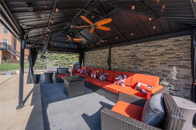 view of patio featuring a gazebo, ceiling fan, fence, and an outdoor hangout area