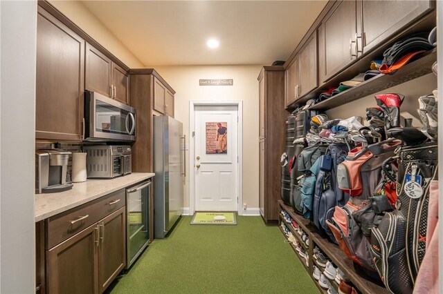 kitchen featuring wine cooler, a toaster, light stone counters, carpet, and appliances with stainless steel finishes