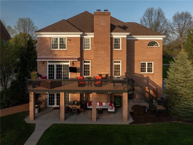 back of house featuring a patio, a chimney, an outdoor hangout area, brick siding, and a lawn
