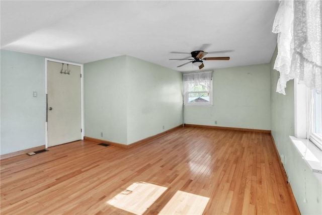unfurnished room with ceiling fan, visible vents, baseboards, and light wood-style floors
