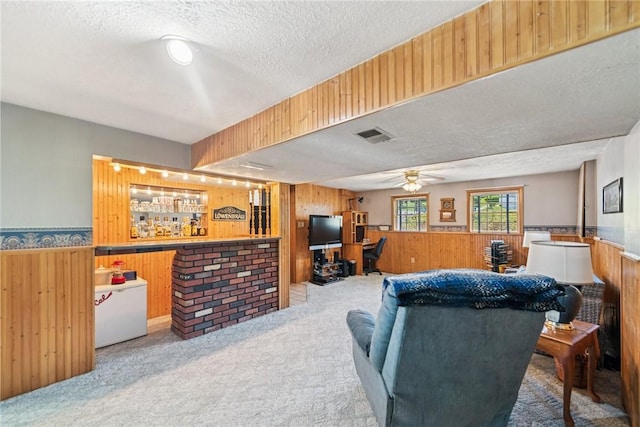 living room featuring carpet flooring, a textured ceiling, wainscoting, and wooden walls