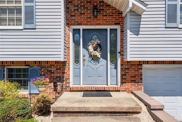 property entrance with an attached garage and brick siding