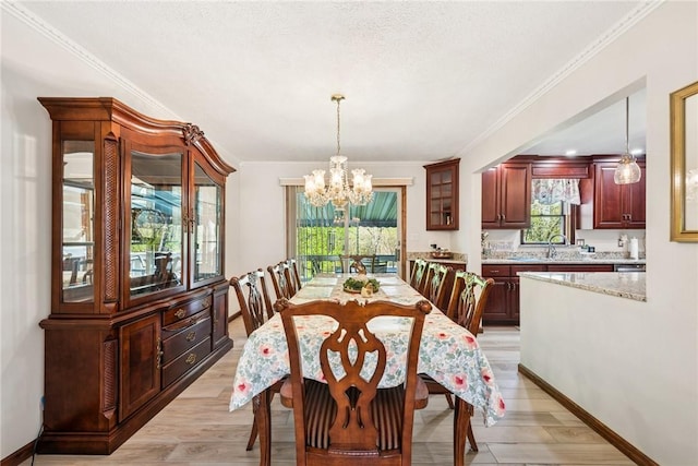 dining room featuring a healthy amount of sunlight, ornamental molding, light wood-style flooring, and a notable chandelier