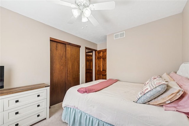 bedroom featuring a closet, ceiling fan, light colored carpet, and visible vents