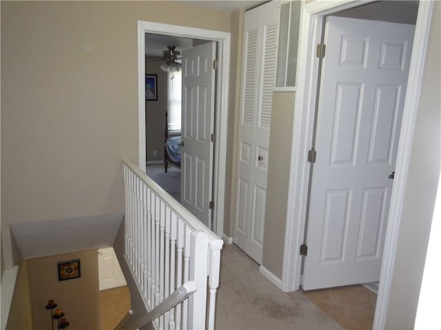 corridor with baseboards, light colored carpet, and an upstairs landing