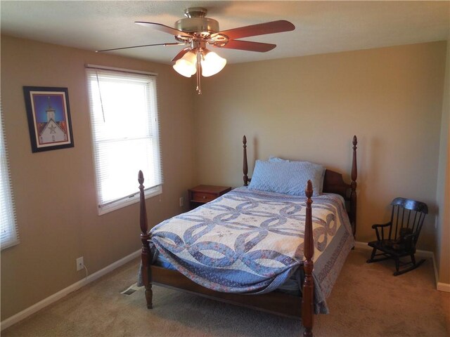 bedroom with baseboards, multiple windows, ceiling fan, and light carpet