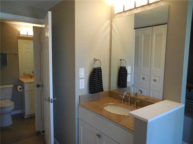 bathroom with a closet, a sink, two vanities, and toilet