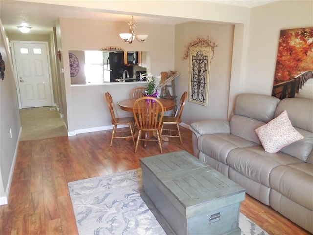 living room featuring baseboards, an inviting chandelier, and wood finished floors