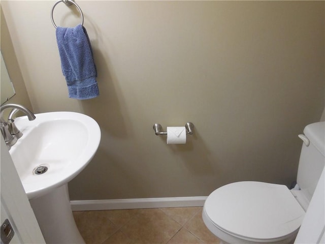 half bath featuring baseboards, tile patterned flooring, and toilet