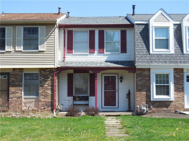 multi unit property with covered porch, brick siding, and a front lawn