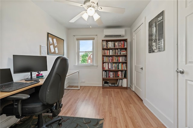 home office featuring baseboards, a wall unit AC, a ceiling fan, and light wood-style flooring