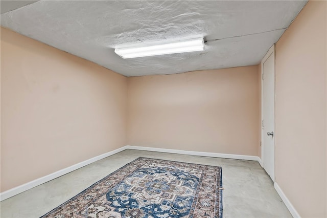 spare room featuring concrete flooring and baseboards
