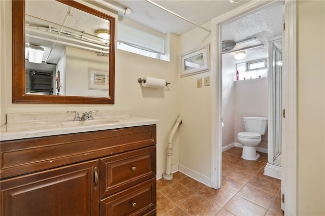 bathroom with tile patterned flooring, vanity, toilet, a textured ceiling, and baseboards