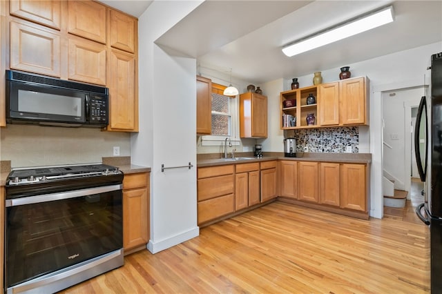 kitchen featuring open shelves, black microwave, a sink, light wood-style flooring, and gas range