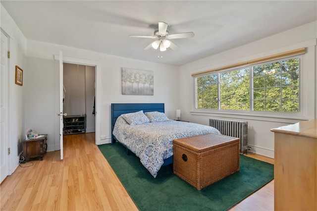 bedroom featuring light wood-style floors, ceiling fan, and radiator heating unit