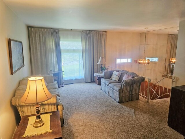 carpeted living area featuring an inviting chandelier