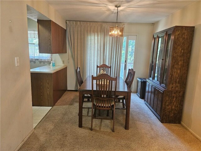 dining area featuring baseboards, a notable chandelier, and light carpet