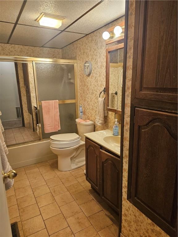 bathroom featuring tile patterned flooring, vanity, toilet, wallpapered walls, and combined bath / shower with glass door