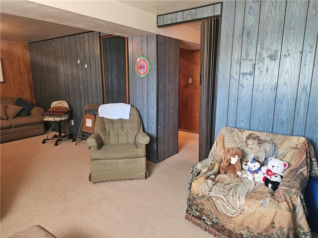 sitting room featuring wood walls and carpet flooring