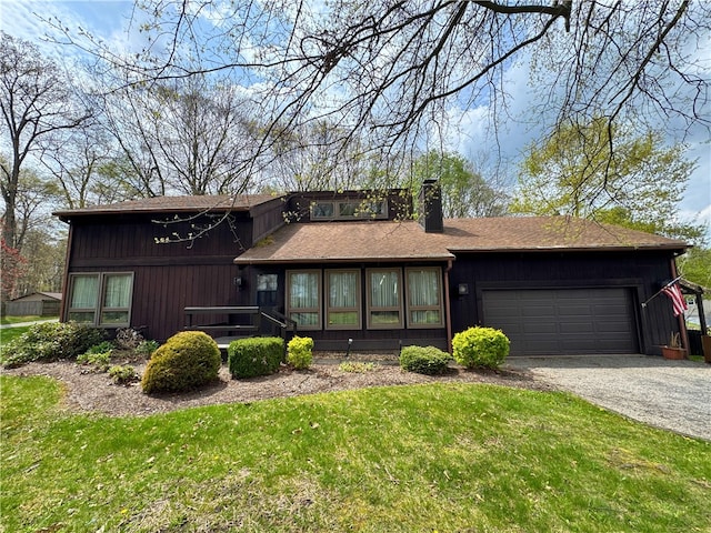 view of front of property with a front lawn, a chimney, a shingled roof, an attached garage, and driveway