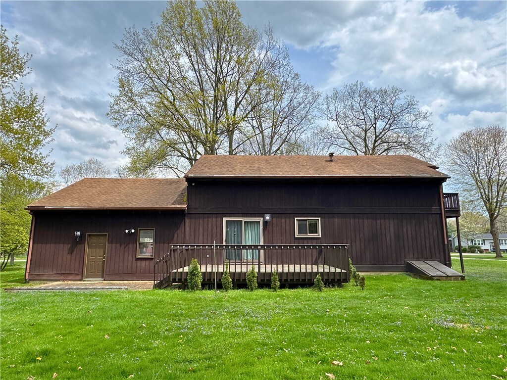 back of house featuring a yard, a deck, and a shingled roof
