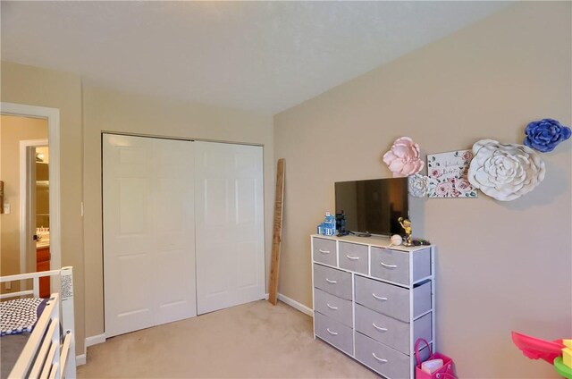 bedroom with baseboards, light carpet, and a closet