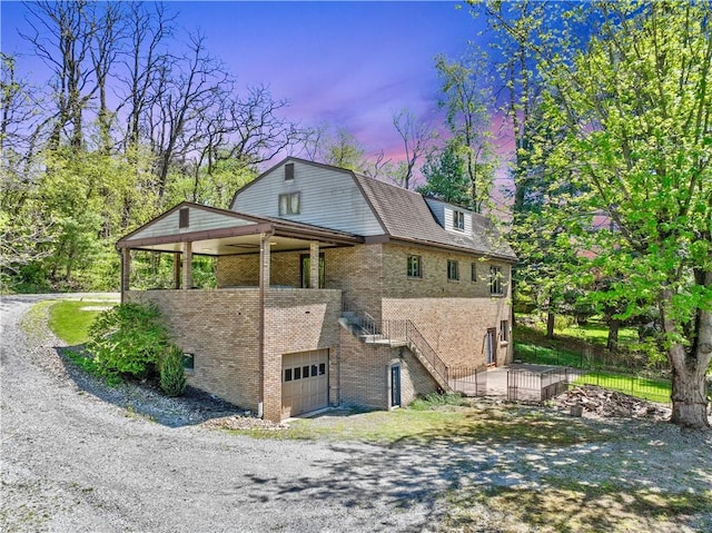 2408 Georgette St, Overbrook, PA 15234 - property exterior at dusk featuring brick siding, a gambrel roof, driveway, and a garage