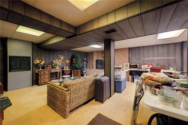 living area featuring carpet floors, wood walls, and visible vents