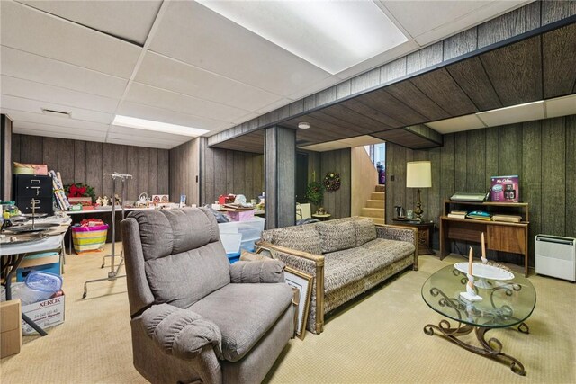 living room with wooden walls, carpet floors, stairs, and visible vents