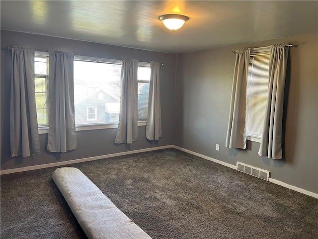 carpeted empty room featuring baseboards, visible vents, and plenty of natural light