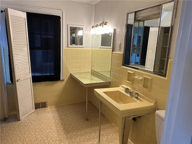 bathroom with visible vents, toilet, tile walls, a wainscoted wall, and tile patterned floors