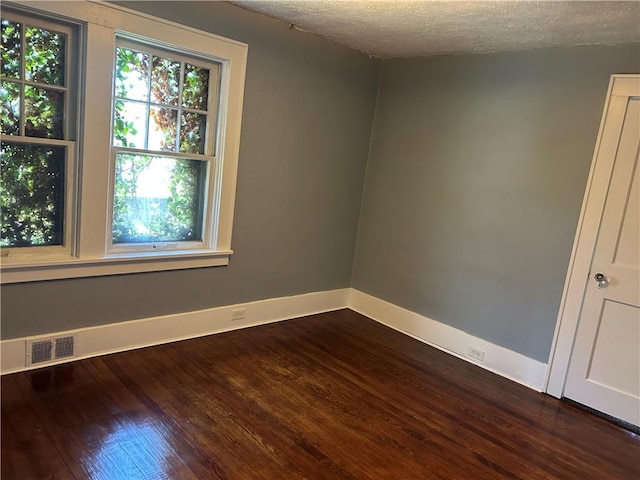 unfurnished room featuring visible vents, baseboards, and dark wood finished floors