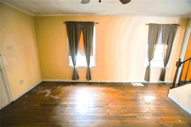 empty room with visible vents, a ceiling fan, a healthy amount of sunlight, and hardwood / wood-style flooring