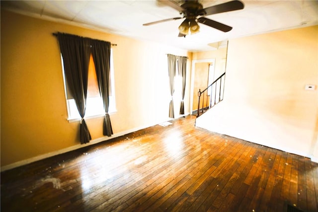 unfurnished living room featuring wood-type flooring, a ceiling fan, and stairway