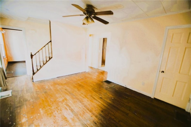 unfurnished living room featuring ornamental molding, wood-type flooring, stairs, and ceiling fan