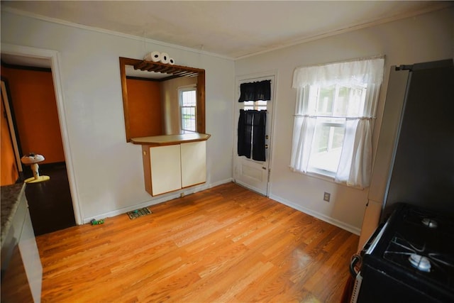 interior space with baseboards, visible vents, ornamental molding, and light wood-type flooring