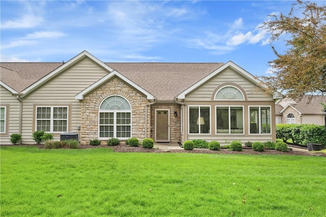 view of front facade featuring roof with shingles, stone siding, and a front yard