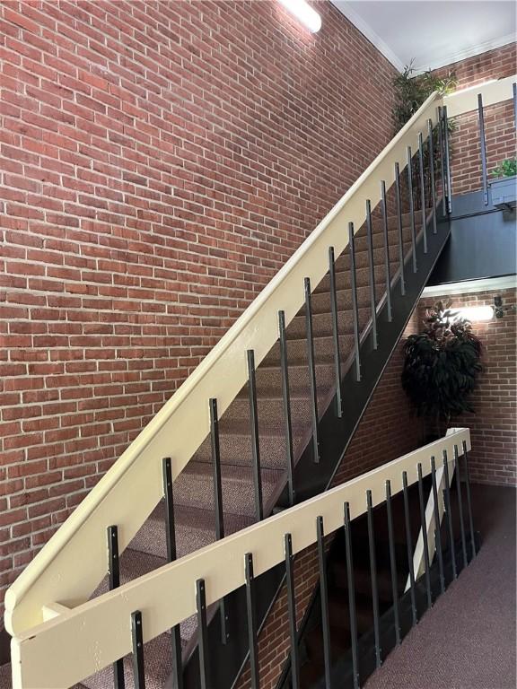 stairs with carpet flooring and brick wall