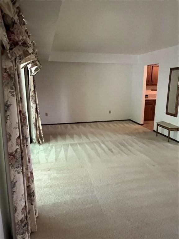 unfurnished room featuring baseboards and light colored carpet