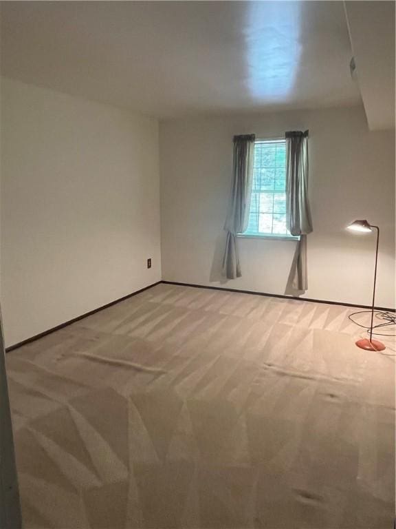 carpeted empty room featuring baseboards