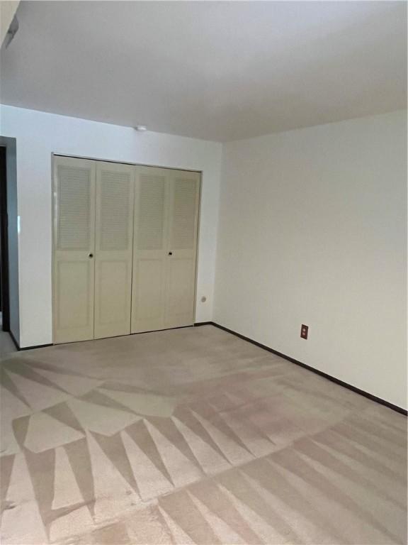 unfurnished bedroom featuring light carpet and a closet
