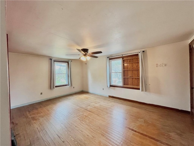 unfurnished room featuring wood-type flooring, a ceiling fan, and baseboards
