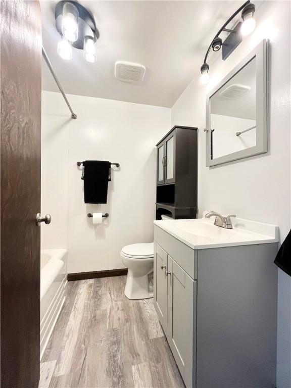 full bath featuring vanity, visible vents, wood finished floors, toilet, and  shower combination