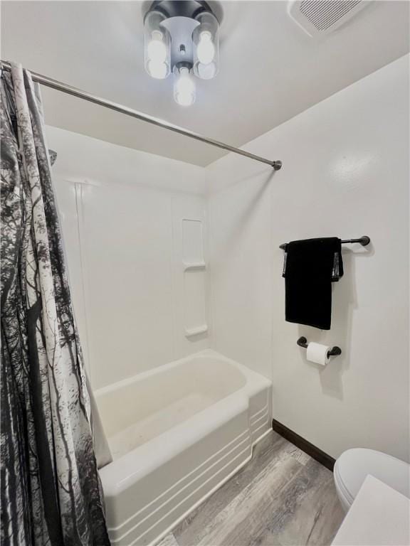 bathroom with toilet, baseboards, wood finished floors, shower / tub combo, and visible vents