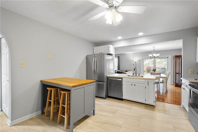 1470 Yorktown Dr, Cecil, PA 15055 - kitchen featuring white cabinets, a peninsula, appliances with stainless steel finishes, and ceiling fan with notable chandelier