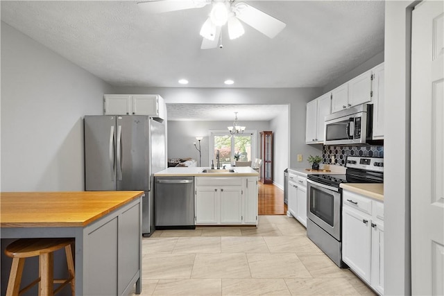 1470 Yorktown Dr, Cecil, PA 15055 - kitchen featuring a peninsula, ceiling fan with notable chandelier, white cabinets, a sink, and appliances with stainless steel finishes