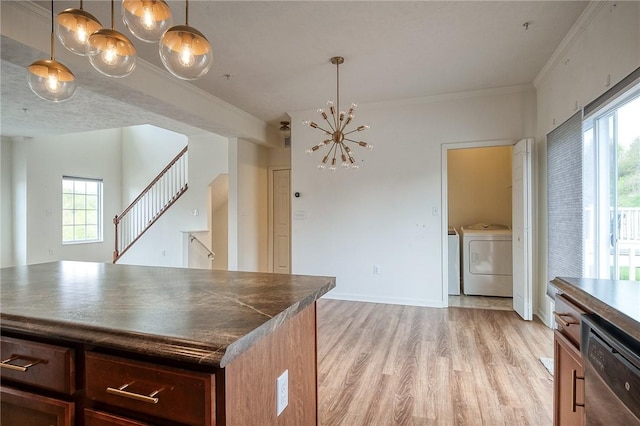 kitchen featuring dark countertops, a notable chandelier, light wood finished floors, stainless steel dishwasher, and washing machine and dryer