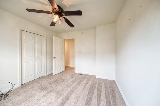 unfurnished bedroom with a closet, baseboards, ceiling fan, and carpet flooring